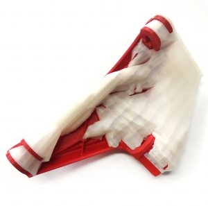 A part (in red) 3D-printed on a Stratasys fused deposition modeling (FDM) machine, with the temporary support structure (in white) still attached. (Image courtesy PostProcess)