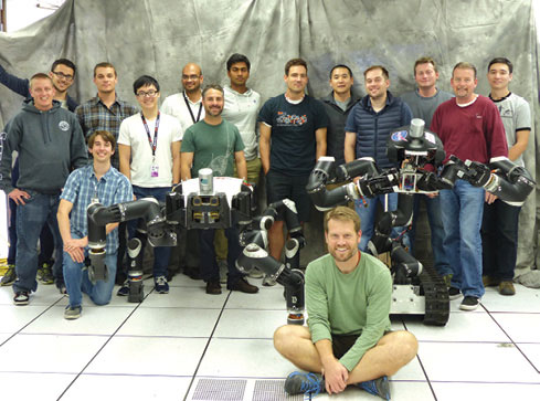 Robotics researchers at NASA’s Jet Propulsion Laboratory pose with robots RoboSimian and Surrogate. Image courtesy of JPL-Caltech.