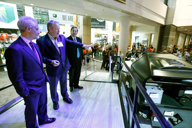 Chicago mayor Rahm Emanuel (left) received a tour of AMT’s Emerging Technology Center on Wednesday. Dr. Craig Blue (center), CEO of the Institute for Advanced Composites Manufacturing Innovation, describes how this hybrid utility vehicle can be wirelessly charged. Image courtesy of IMTS. 